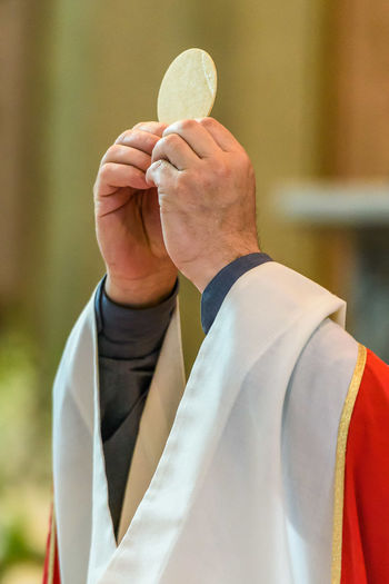 Cropped hands of priest holding bread in church