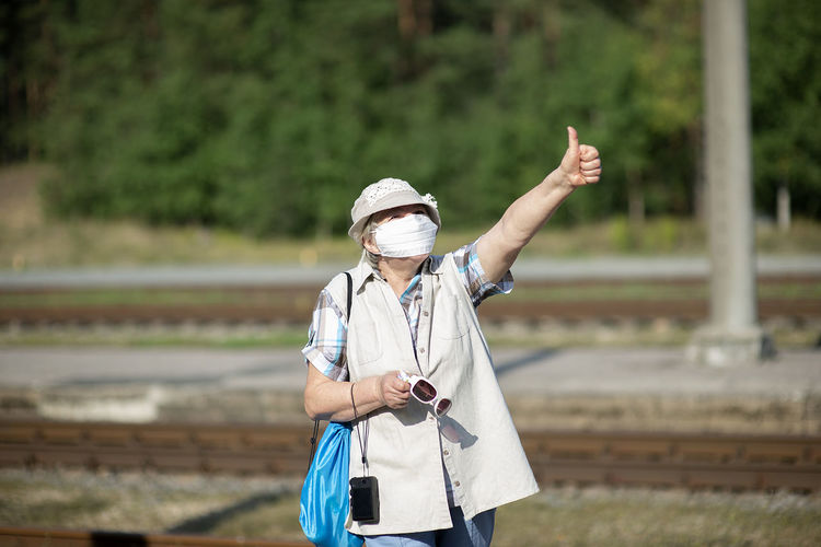 Positive old senior elderly woman with medical face mask,hat and photo camera