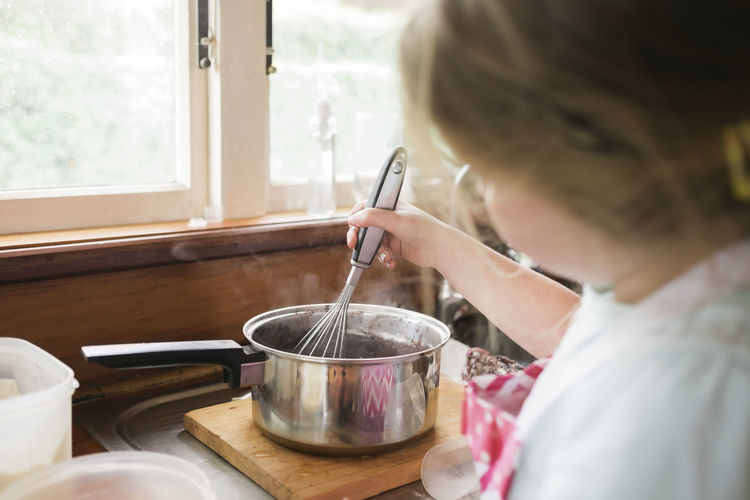 Young girl whisking hot baking mixture in a pot