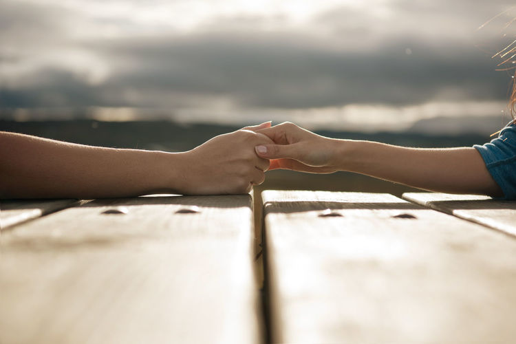 Cropped image of man and woman holding hands on table