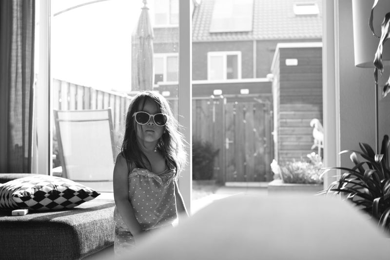 Girl wearing sunglasses standing at home