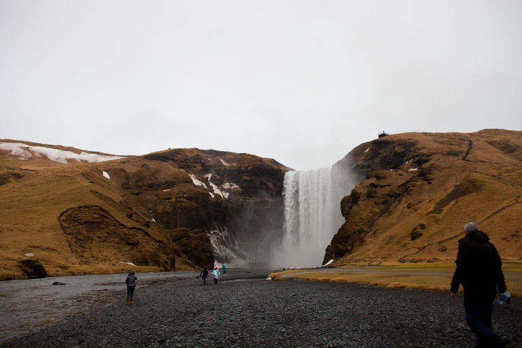 People visiting skogafoss against sky