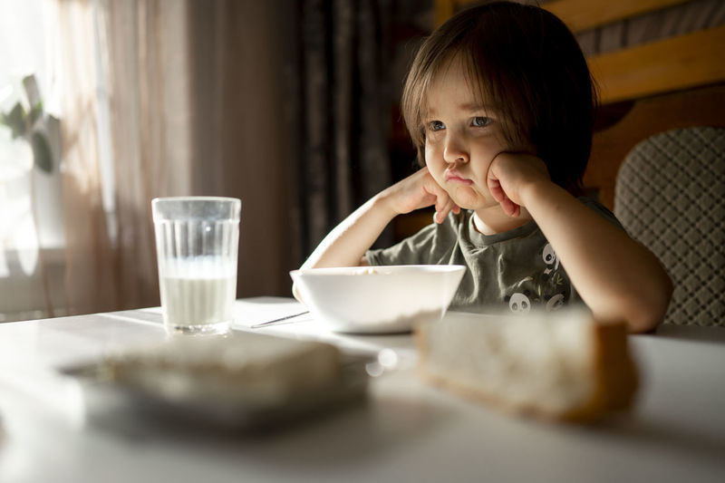 Upset boy with food on dining table at home
