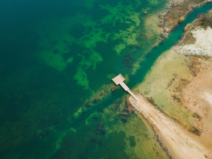 Shallow water coast and wooden bridge with the beach in quarry lake.