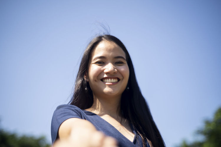 Portrait of a smiling young woman against blue sky