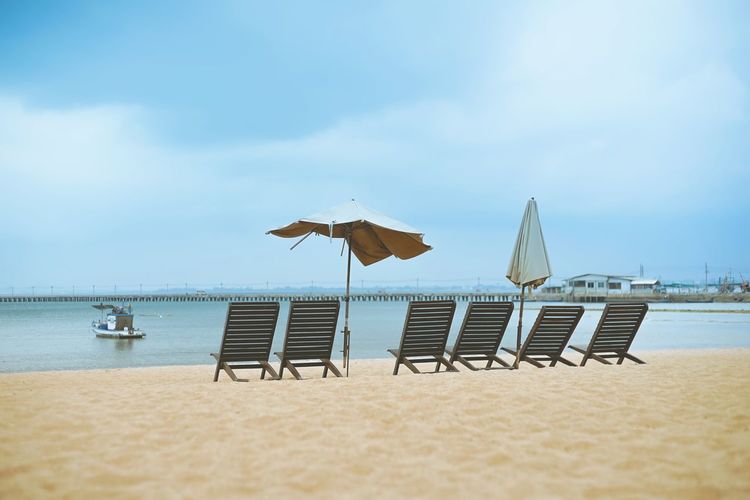 Chairs on beach against sky