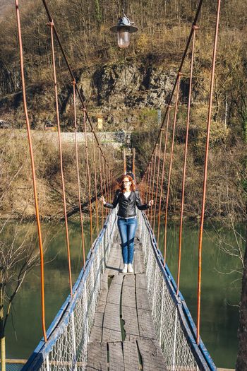 Woman standing on footbridge over river