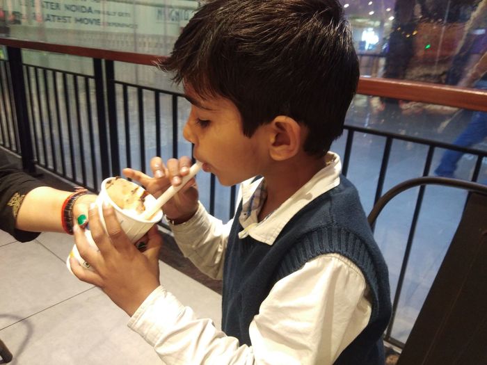 Portrait of boy holding ice cream railing