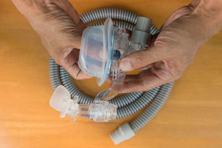 Close-up of hands holding oxygen mask at wooden table