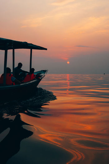 People in boat against sky during sunset