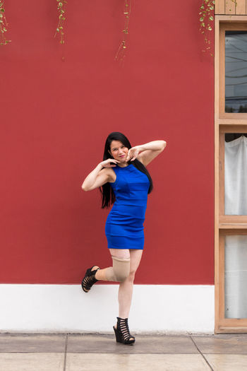 Full length of woman using standing against red wall