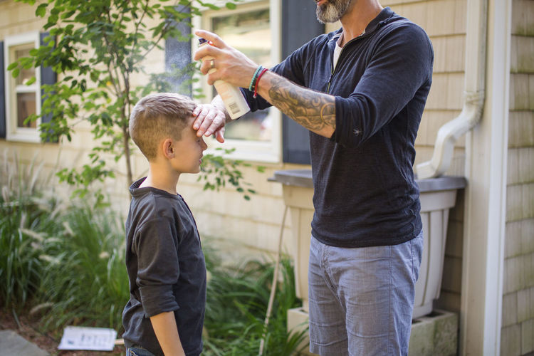 A father applying sunscreen to his son in the backyard
