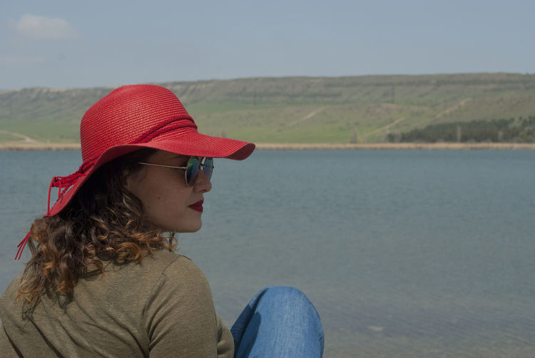 Woman wearing hat while sitting on land
