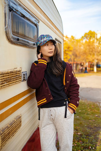 Portrait of young asian woman standing against camper
