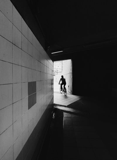 Silhouette man walking on footpath in tunnel