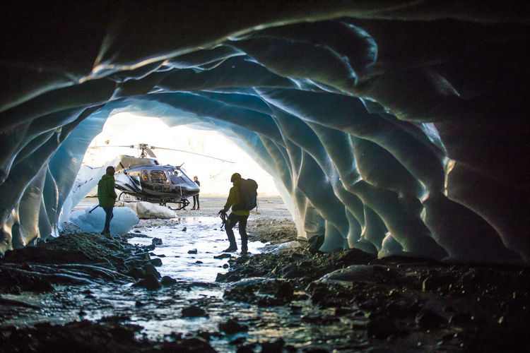 Couple exploring ice cave during helicopter tour.