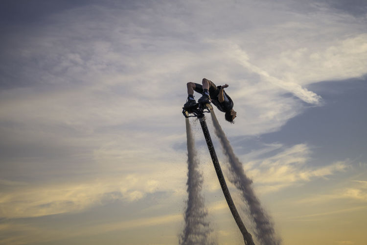Low angle view of man flyboarding against sky