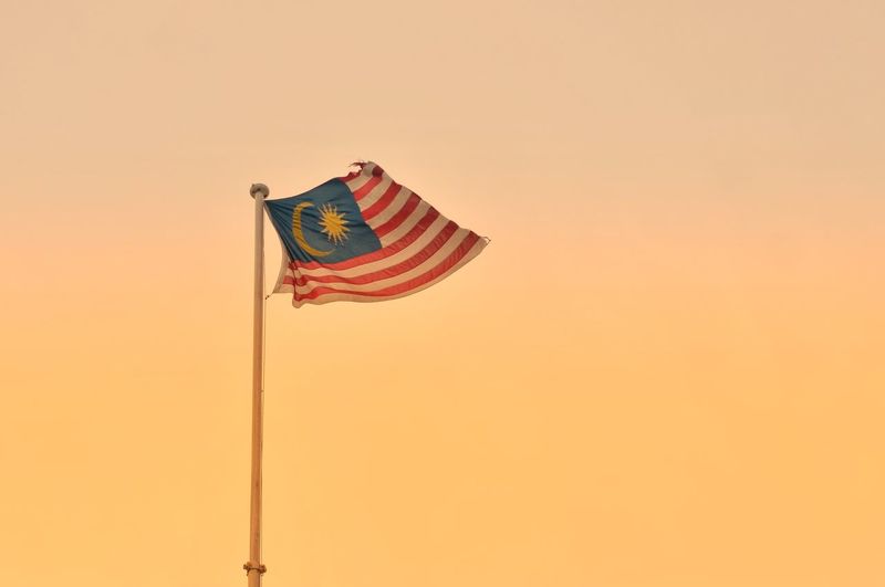 Low angle view of malaysian flag against orange sky
