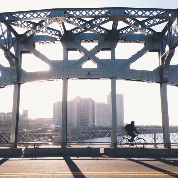 Man cycling on bridge against sky