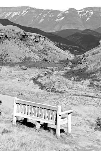 Empty bench on field against mountains
