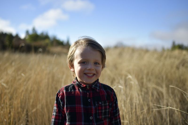 Portrait of toddler boy standing in tall grass 