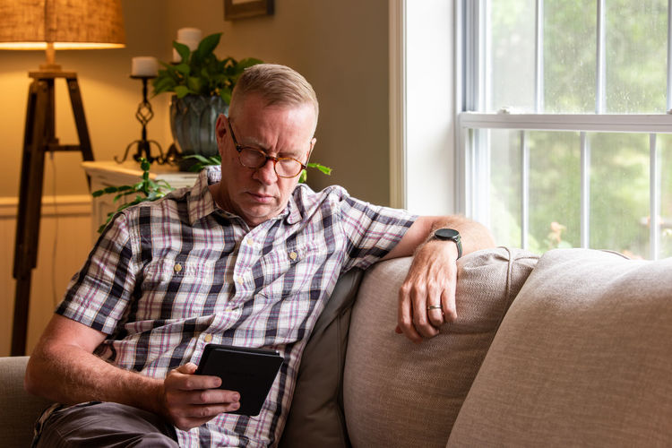Senior man using digital tablet while sitting on sofa at home