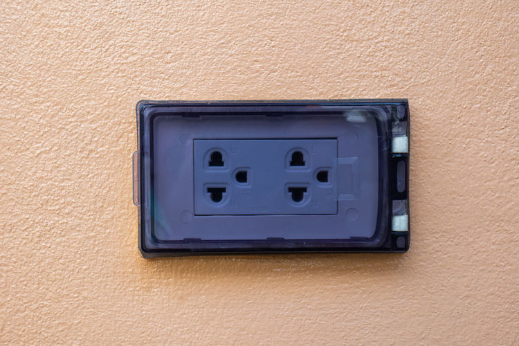 An outlet with a safety cover was installed side-to-side into the egg-colored wall.
