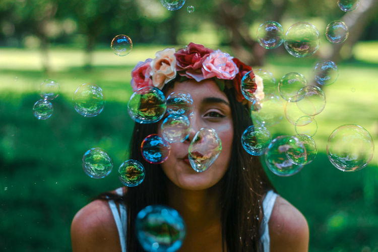 Close-up portrait of young woman blowing bubbles