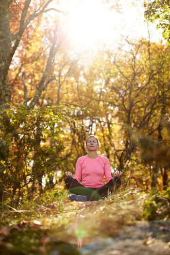 An athletic woman meditates outdoors on a beautiful autumn day.