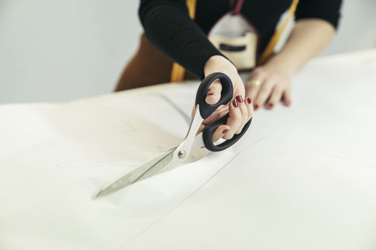 Hand of fashion designer cutting cloth