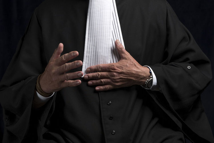 Midsection of lawyer standing against black background