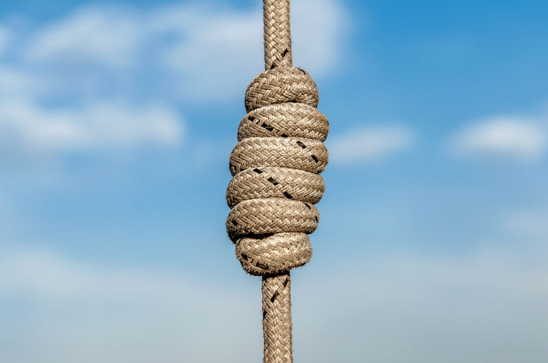 Close-up of rope tied on wooden post against sky