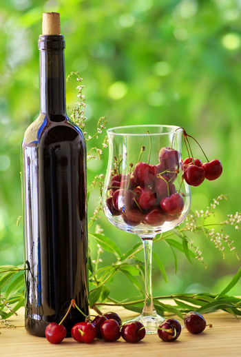 Wine bottle and cherries inside wineglass 