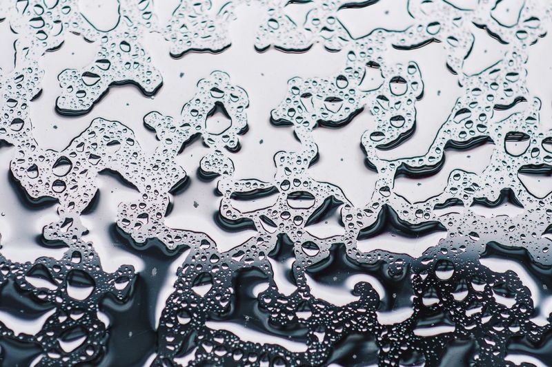 Backlit full frame shot of water drops on glass