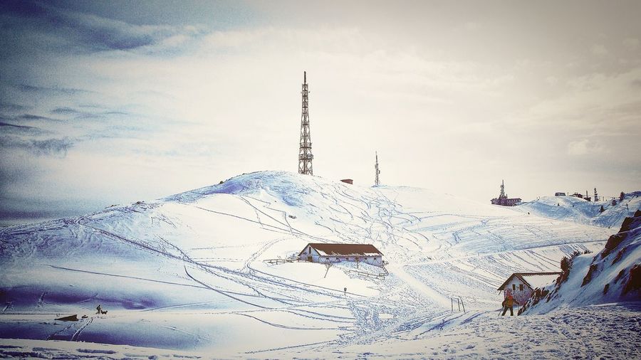 Flock of birds on snow covered field against sky