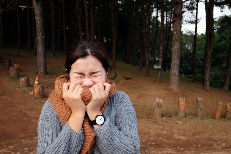 Young woman wearing warm clothing with eyes closed in forest