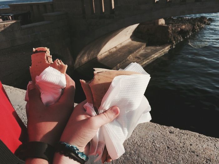 Cropped image of couple holding crepe against river