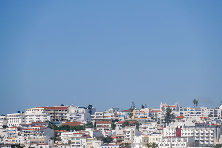 Buildings in city against clear blue sky