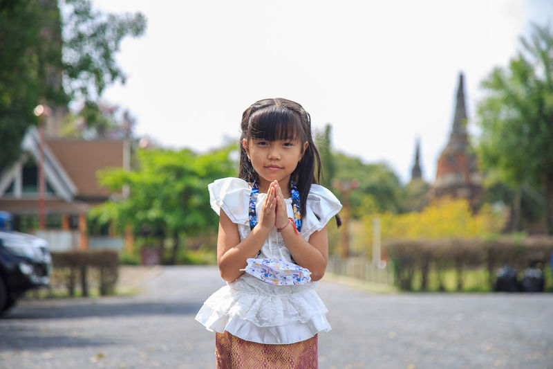 Portrait of asian girl in a white thai shirt pay respect with an old pagoda background