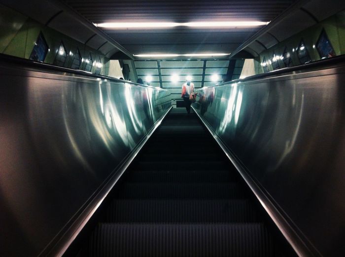 Man on escalator in illuminated underground walkway