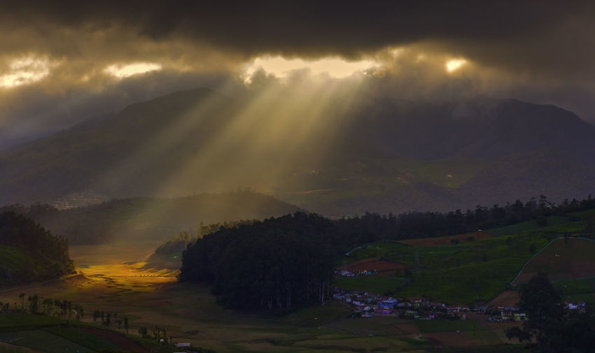 High angle view of sun shining through clouds over landscape