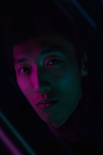 Close-up portrait of young woman against black background