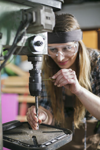 Close-up of woman using machinery in workshop