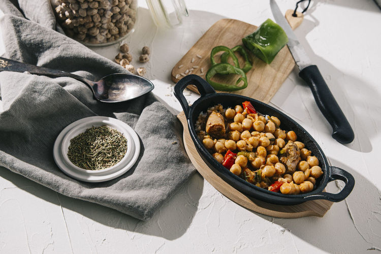 Top shot of chickpea stew iron pan with ingredients in a white table