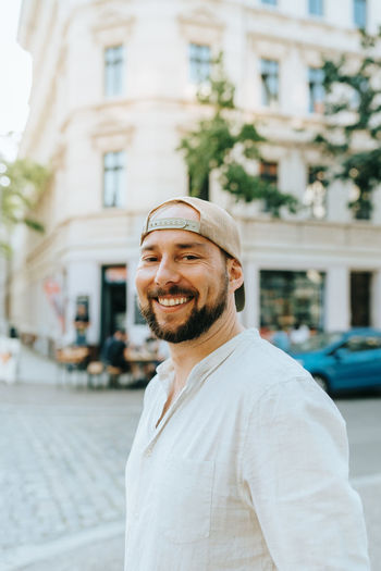Portrait of smiling man standing on street against buildings in city
