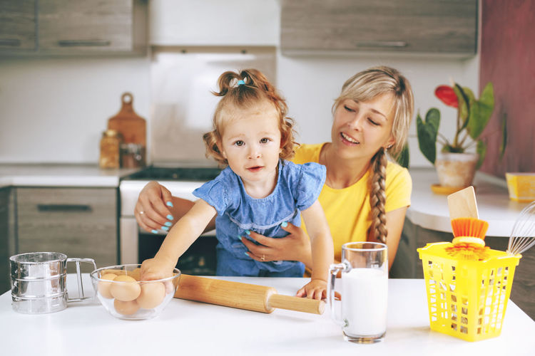 Portrait of cute girl with mother at kitchen