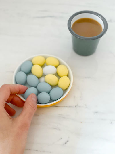 High angle view of hand holding eggs in bowl on table