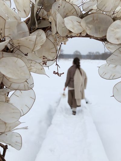 Rear view of woman walking on snow covered tree