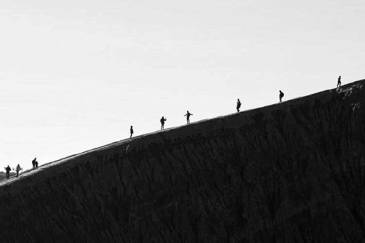 Low angle view of people walking on land against clear sky