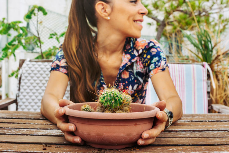 Young woman sitting on potted plant